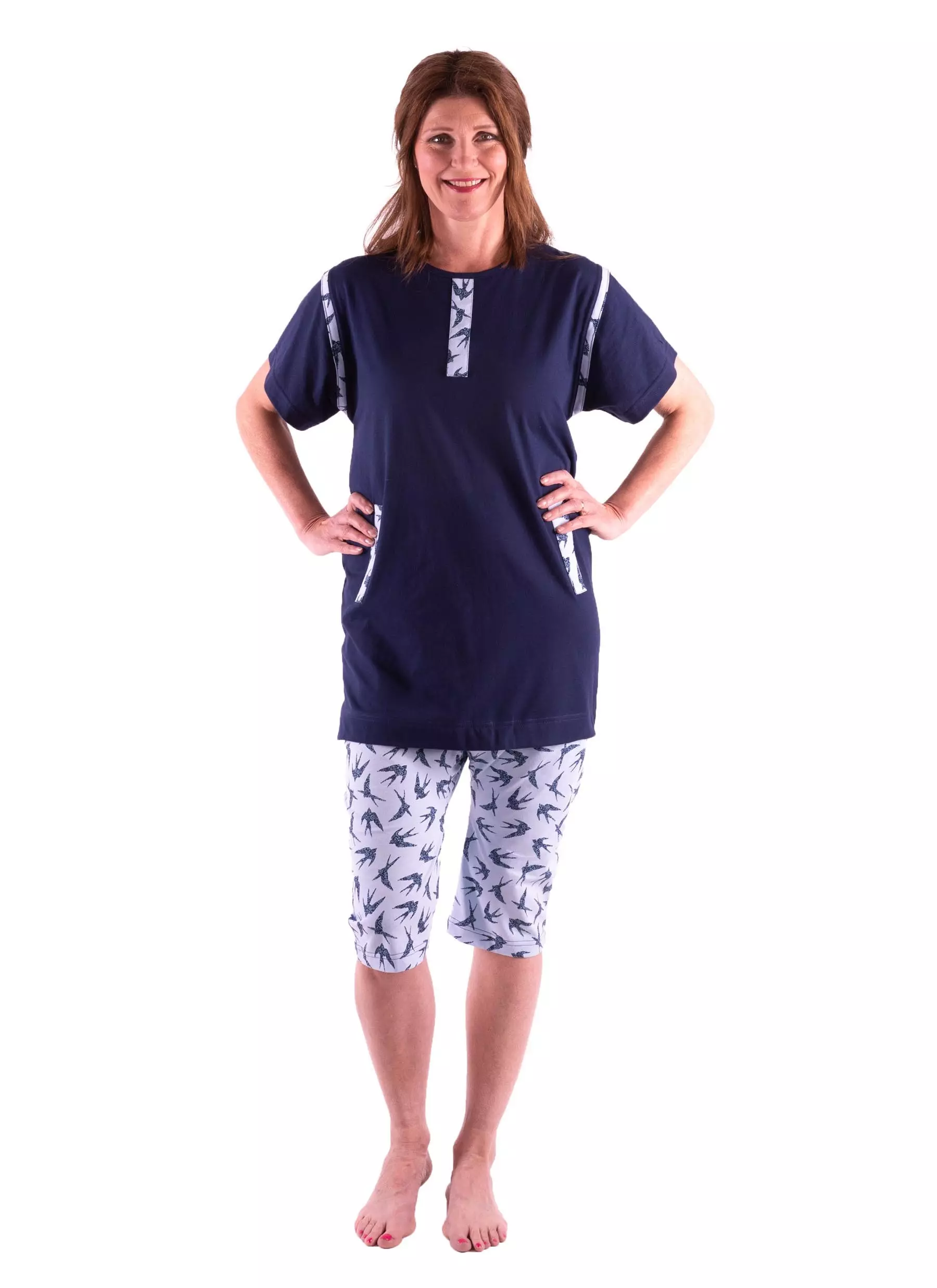 Pflegeoverall 1054 von 4Care für Damen, marineblaues Oberteil und gemusterte Hose, kurzarm, mit Rückenreißverschluss, verhindert selbständiges Entkleiden, weiche Jerseyqualität, 100 % Baumwolle, waschbar bei 60 °C.