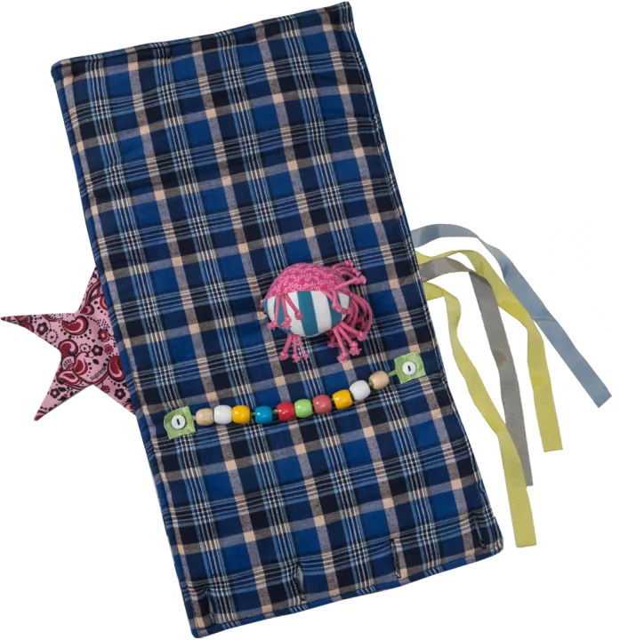 Geöffneter Suprima Demenz-Muff 7150, verwendbar als Decke (55 × 30 cm), zeigt verschiedene Materialien, Knöpfe und Bänder zur sensorischen Stimulation und Beruhigung unruhiger Hände. Waschbar bei 40 °C. (7150)
