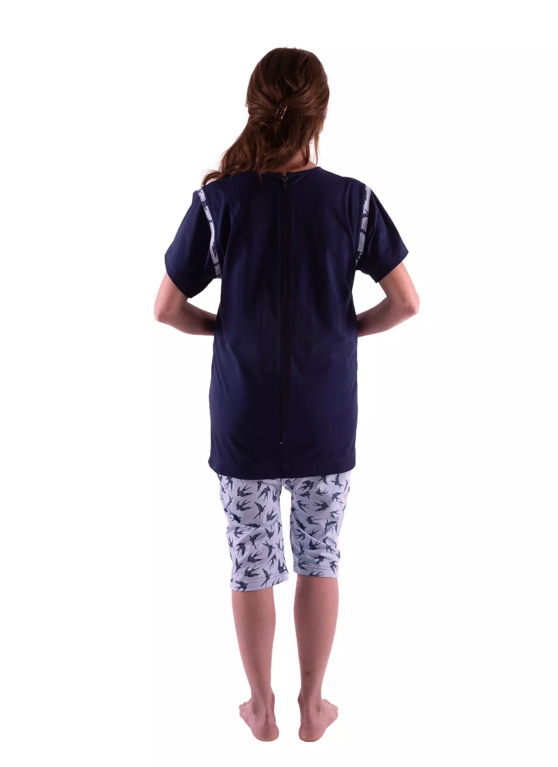 Detailansicht von hinten des Pflegeoverall 1054 von 4Care, zeigt den Rückenreißverschluss, ideal für die Pflege, verhindert selbständiges Entkleiden, marineblaues Oberteil, gemusterte Hose. 